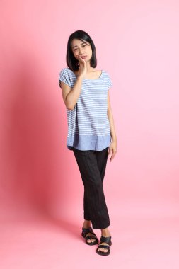 Pembe arka planda duran mavi gömlekli melez kadın..