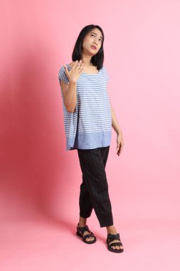 Pembe arka planda duran mavi gömlekli melez kadın..