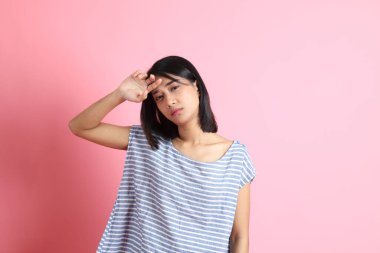 Pembe arka planda duran mavi gömlekli melez kadın..