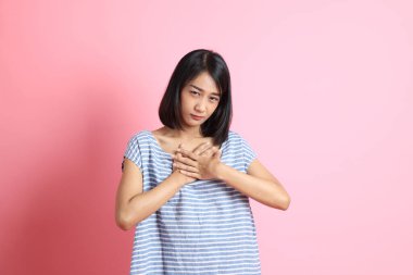 Pembe arka planda duran mavi gömlekli melez kadın..