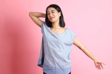 Pembe arka planda duran mavi gömlekli melez kadın..