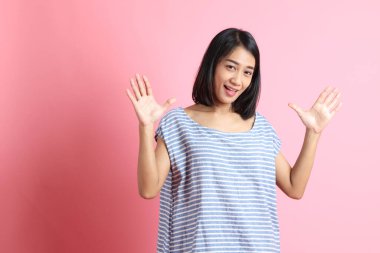 Pembe arka planda duran mavi gömlekli melez kadın..