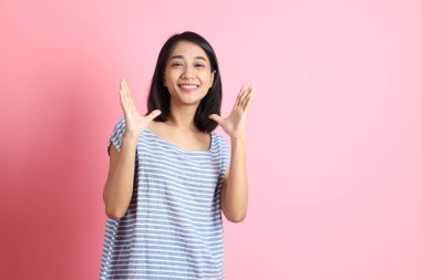 Pembe arka planda duran mavi gömlekli melez kadın..