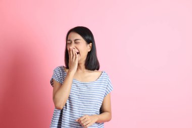 Pembe arka planda duran mavi gömlekli melez kadın..