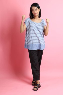 Pembe arka planda duran mavi gömlekli melez kadın..