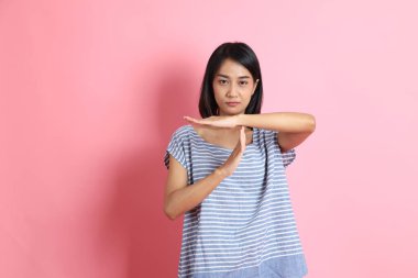 Pembe arka planda duran mavi gömlekli melez kadın..