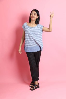 Pembe arka planda duran mavi gömlekli melez kadın..