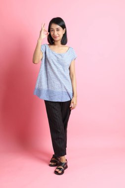 Pembe arka planda duran mavi gömlekli melez kadın..