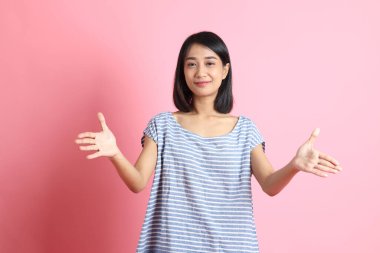 Pembe arka planda duran mavi gömlekli melez kadın..