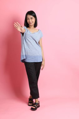 Pembe arka planda duran mavi gömlekli melez kadın..