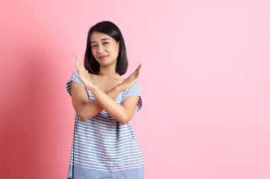 Pembe arka planda duran mavi gömlekli melez kadın..