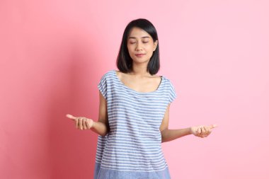 Pembe arka planda duran mavi gömlekli melez kadın..