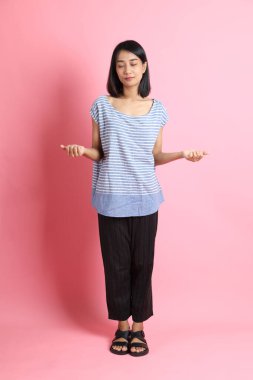 Pembe arka planda duran mavi gömlekli melez kadın..