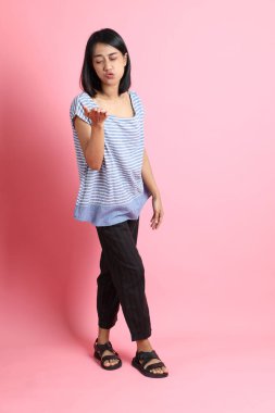 Pembe arka planda duran mavi gömlekli melez kadın..