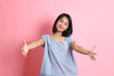 Pembe arka planda duran mavi gömlekli melez kadın..