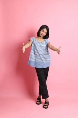 Pembe arka planda duran mavi gömlekli melez kadın..