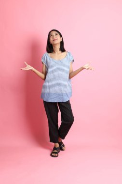 Pembe arka planda duran mavi gömlekli melez kadın..