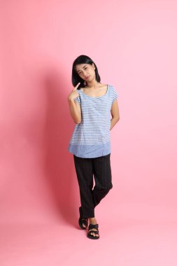 Pembe arka planda duran mavi gömlekli melez kadın..