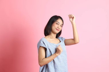 Pembe arka planda duran mavi gömlekli melez kadın..