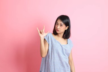 Pembe arka planda duran mavi gömlekli melez kadın..