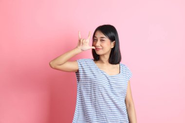 Pembe arka planda duran mavi gömlekli melez kadın..