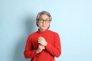 Mavi arka planda duran kıdemli Asyalı adam..