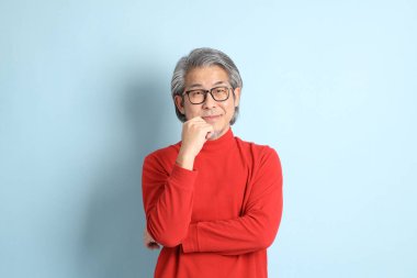 Mavi arka planda duran kıdemli Asyalı adam..