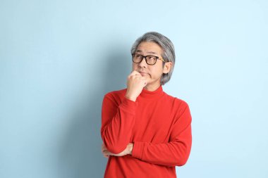 Mavi arka planda duran kıdemli Asyalı adam..