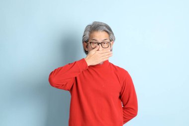 Mavi arka planda duran kıdemli Asyalı adam..