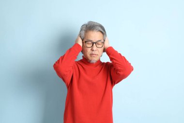 Mavi arka planda duran kıdemli Asyalı adam..