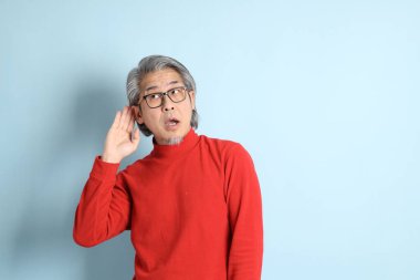 Mavi arka planda duran kıdemli Asyalı adam..