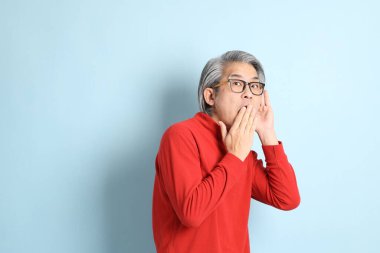 Mavi arka planda duran kıdemli Asyalı adam..