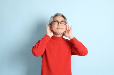 Mavi arka planda duran kıdemli Asyalı adam..