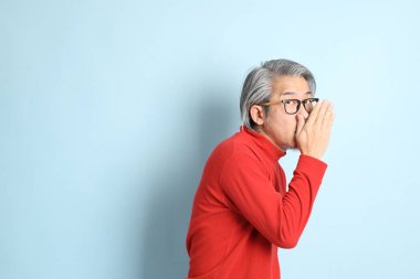 Mavi arka planda duran kıdemli Asyalı adam..