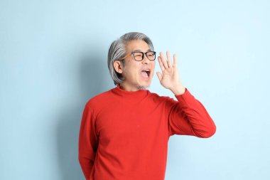 Mavi arka planda duran kıdemli Asyalı adam..