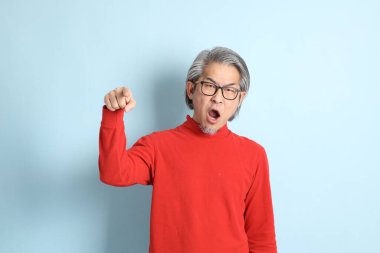 Mavi arka planda duran kıdemli Asyalı adam..