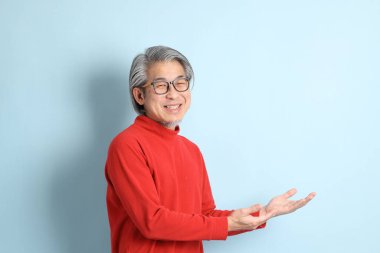 Mavi arka planda duran kıdemli Asyalı adam..