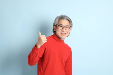 Mavi arka planda duran kıdemli Asyalı adam..