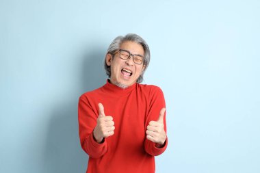 Mavi arka planda duran kıdemli Asyalı adam..