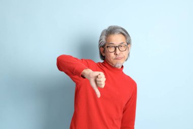 Mavi arka planda duran kıdemli Asyalı adam..