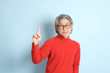 Mavi arka planda duran kıdemli Asyalı adam..