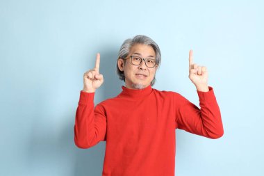 Mavi arka planda duran kıdemli Asyalı adam..