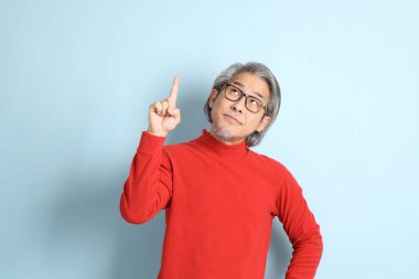 Mavi arka planda duran kıdemli Asyalı adam..