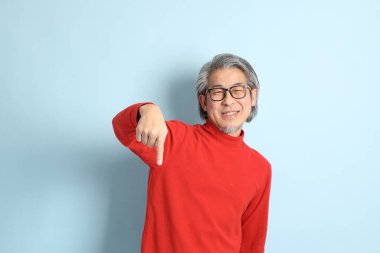 Mavi arka planda duran kıdemli Asyalı adam..