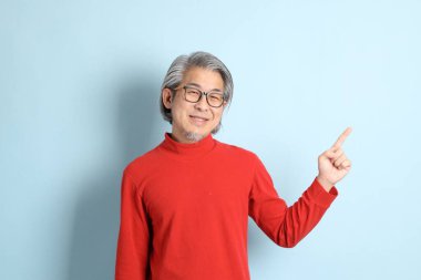 Mavi arka planda duran kıdemli Asyalı adam..