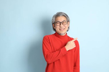 Mavi arka planda duran kıdemli Asyalı adam..