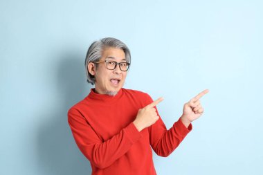 Mavi arka planda duran kıdemli Asyalı adam..