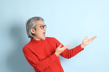 Mavi arka planda duran kıdemli Asyalı adam..