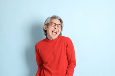 Mavi arka planda duran kıdemli Asyalı adam..