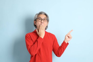 Mavi arka planda duran kıdemli Asyalı adam..